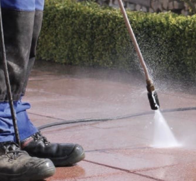 Worker pressure washing a stone patio